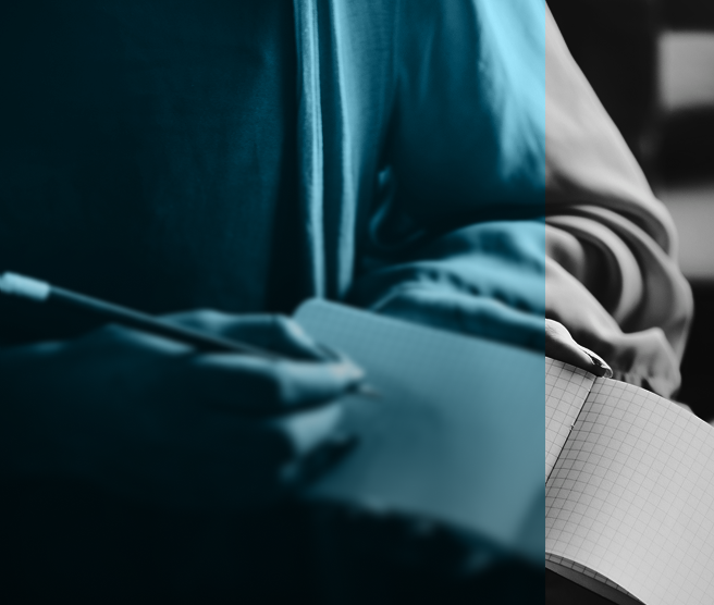 Person writing in a grid-lined notebook with a pencil.