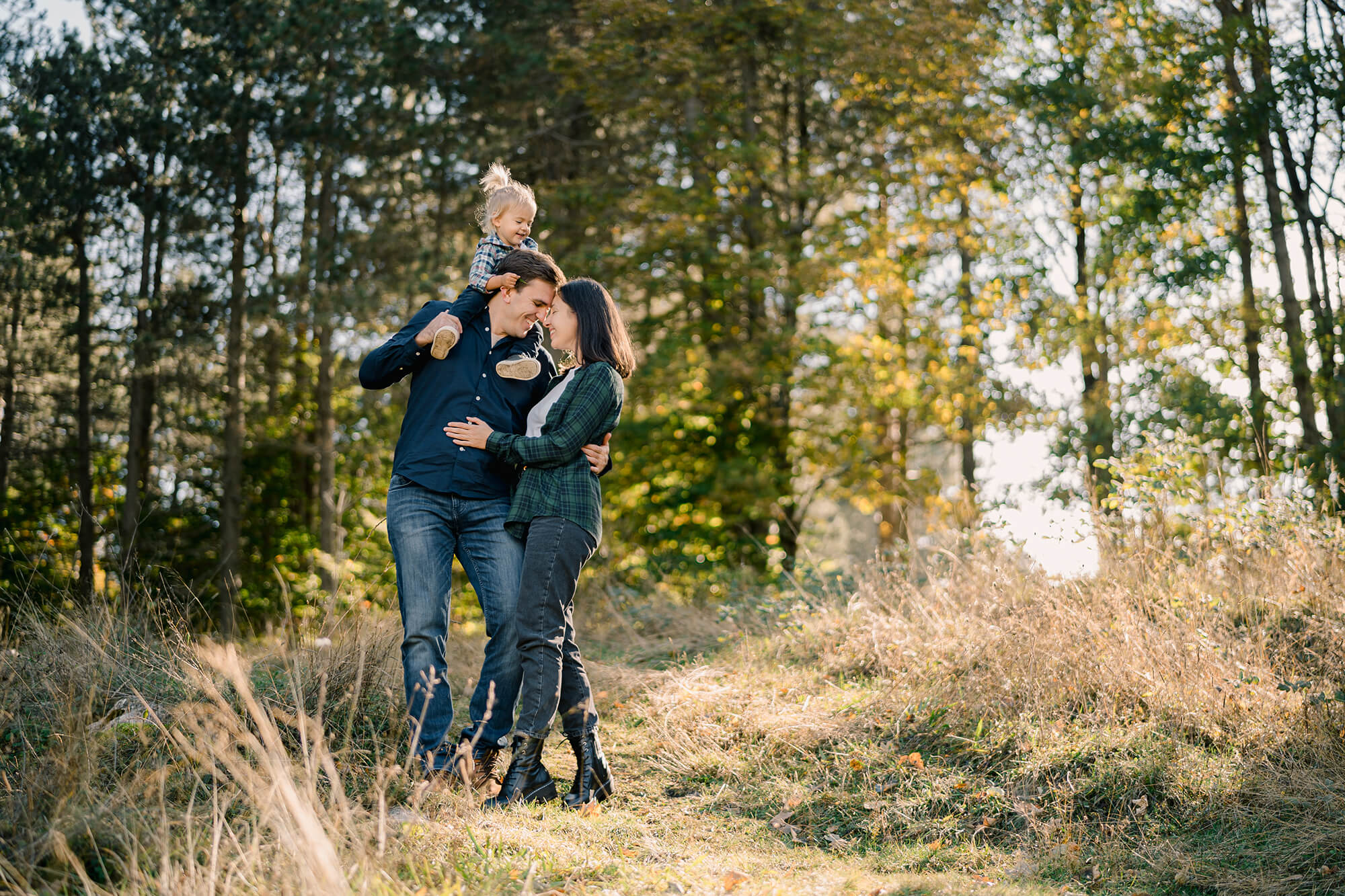 Une famille avec un enfant se baladant dans une forêt, souriants
