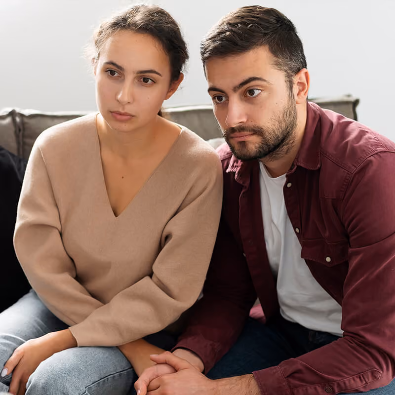 Jeune couple assis sur un canapé face à la sophrologue