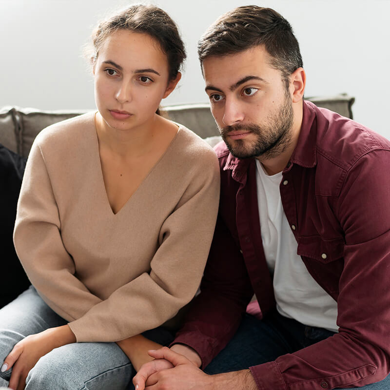Jeune couple assis sur un canapé face à la sophrologue