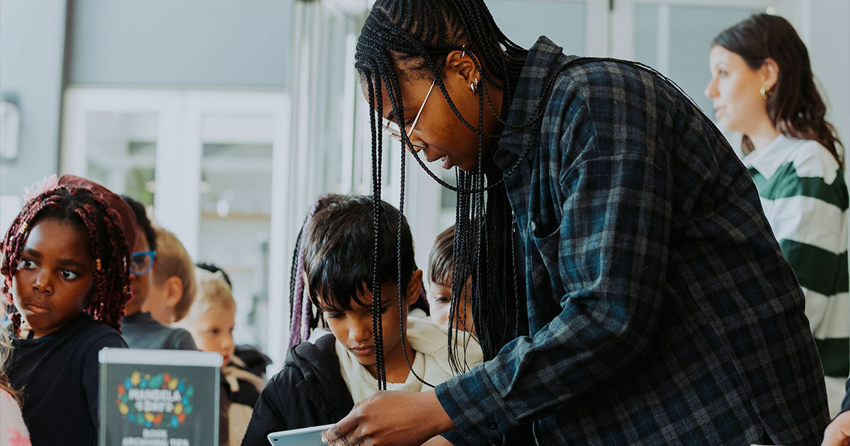 Teacher assisting diverse children in a bright classroom setting.