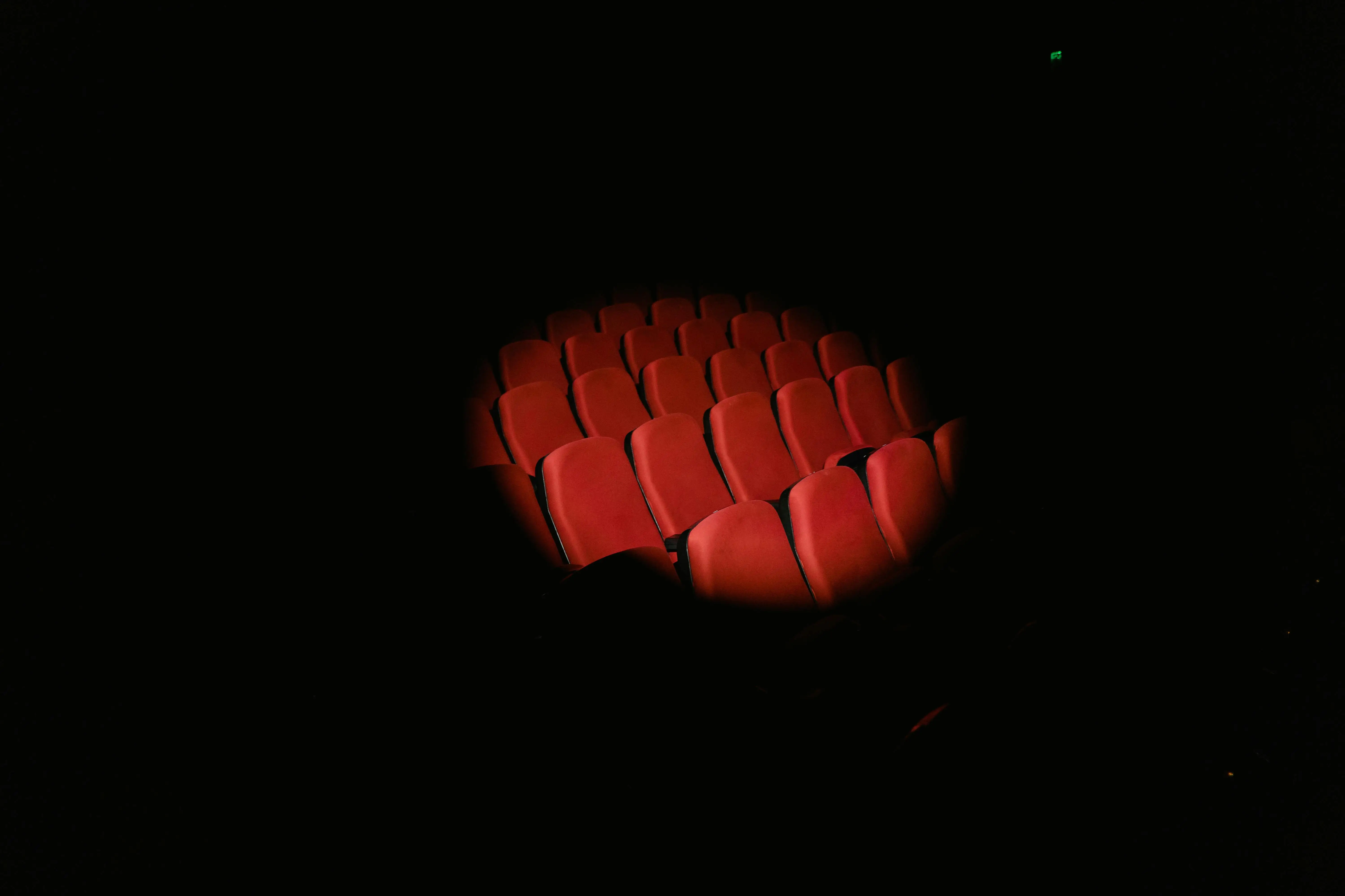 Empty red theater seats illuminated in dark cinema auditorium