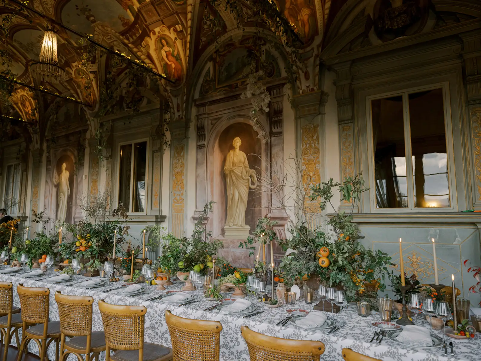Elegant dining room with ornate ceiling, statues, and lavish table setting in Tuscany