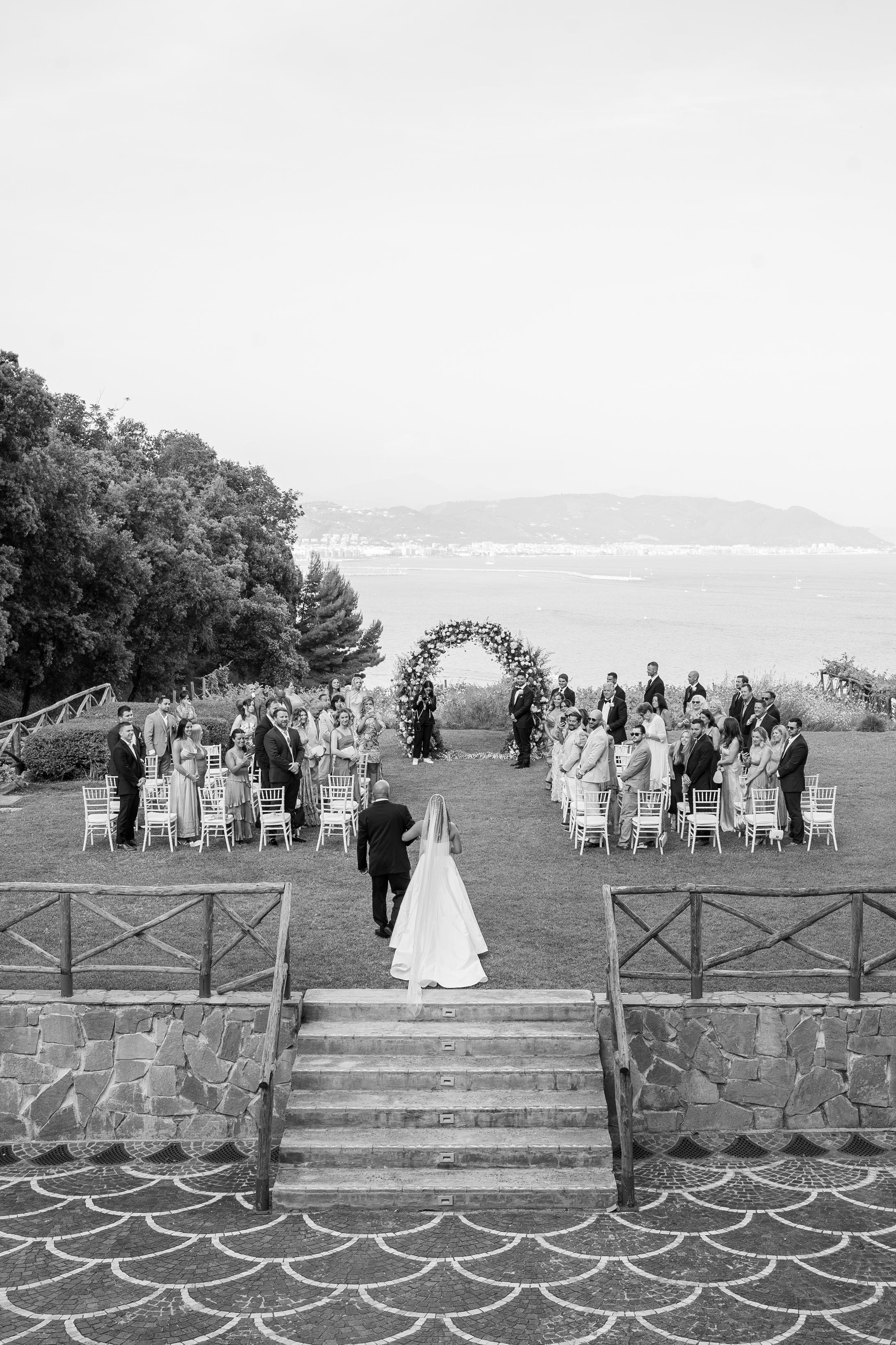 Outdoor wedding ceremony with ocean view and floral arch