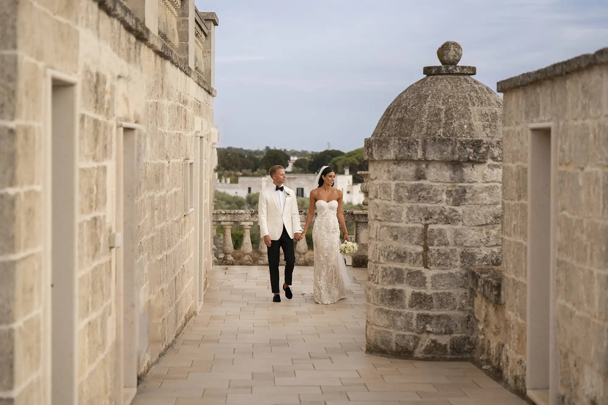 Wedding couple walking hand in hand through historic stone courtyard