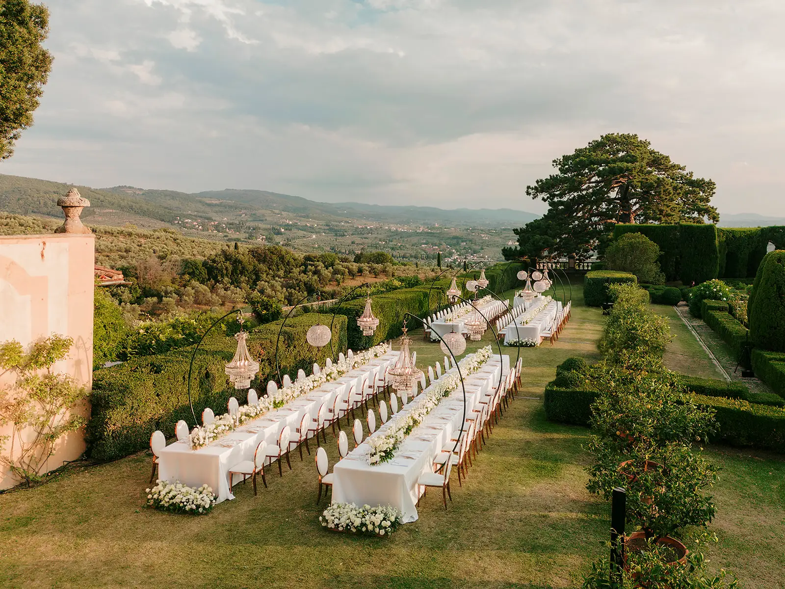 Elegant outdoor wedding reception with long tables in manicured garden landscape