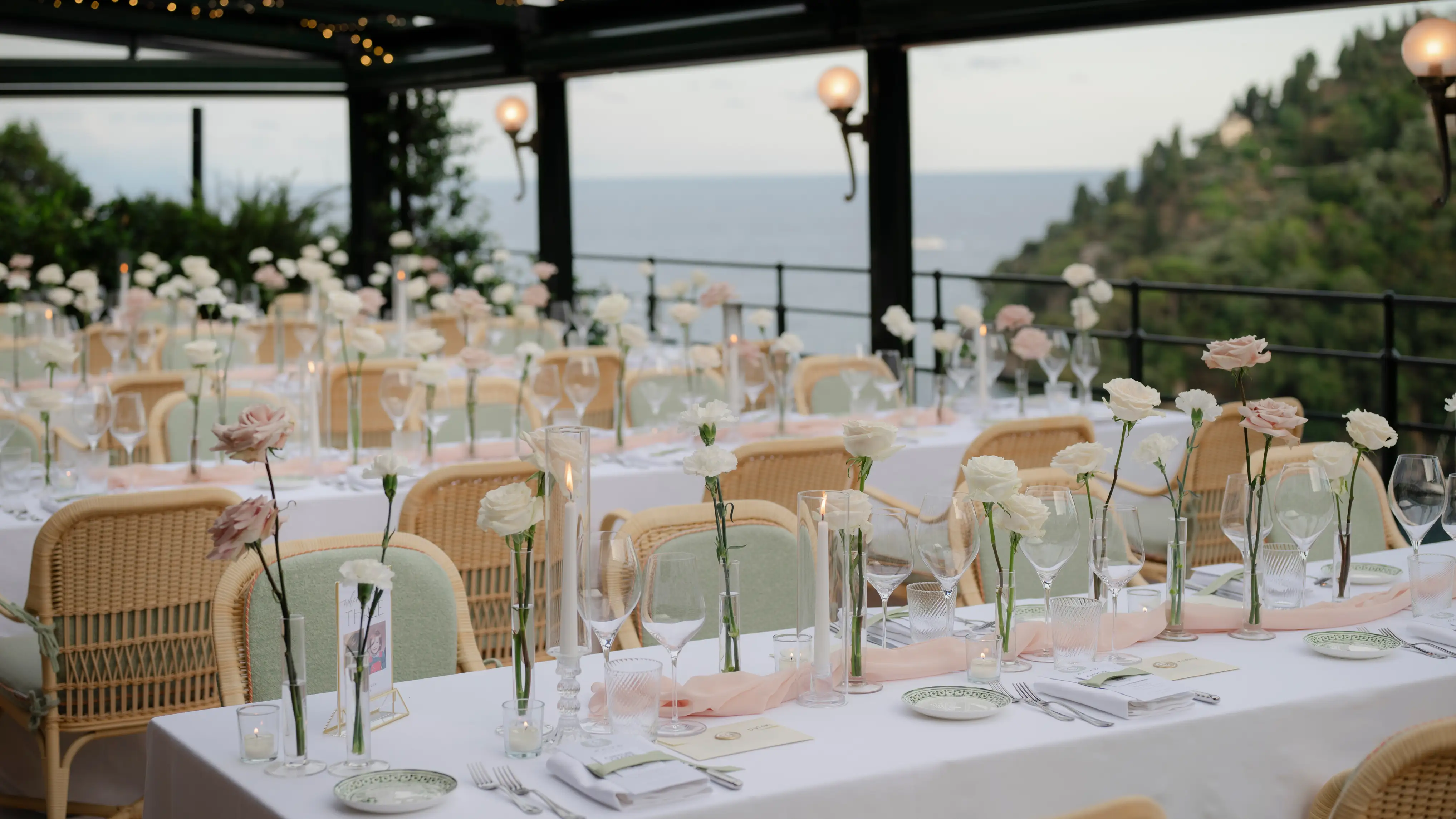 Elegant wedding reception setup with ocean view and blush-colored flowers