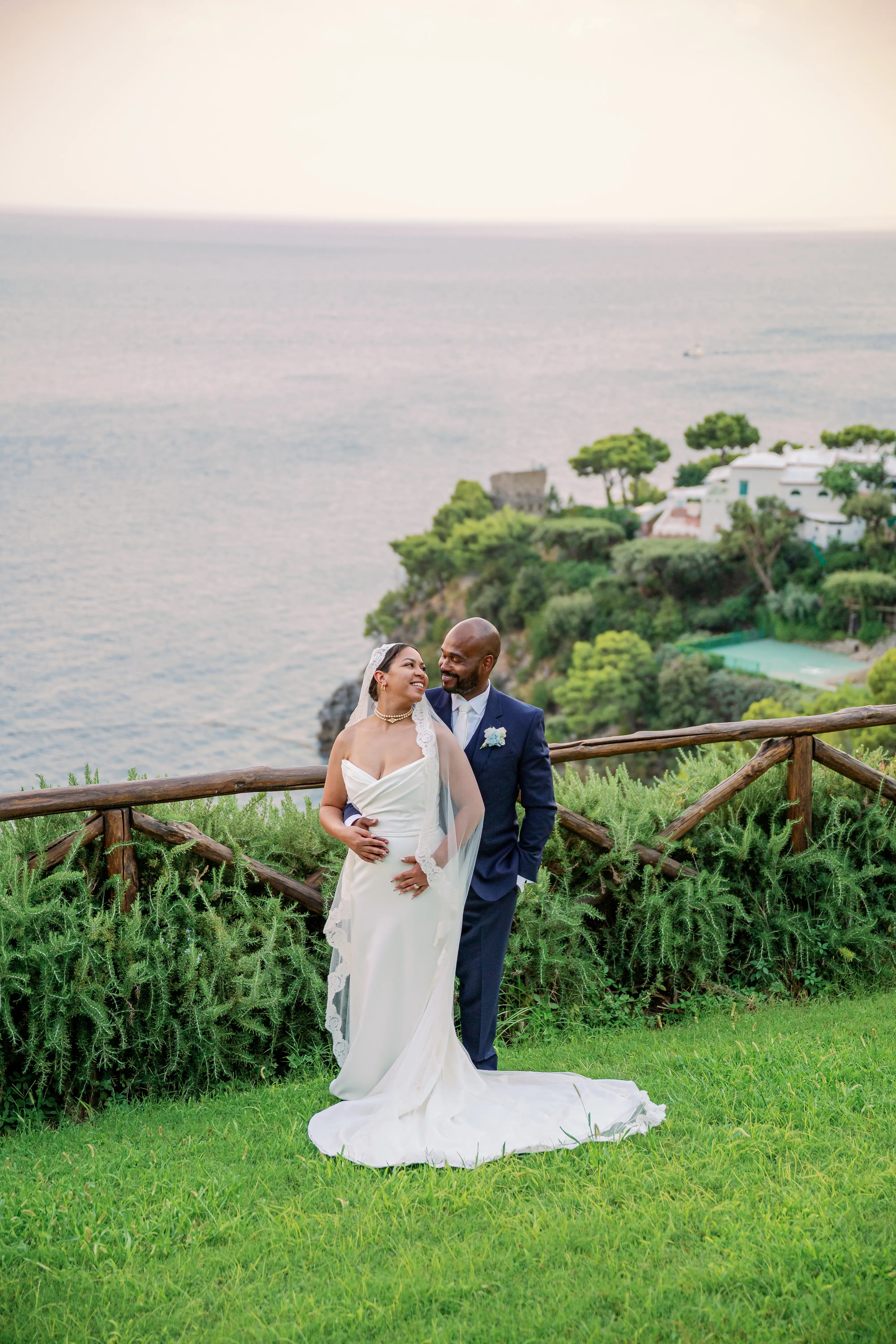Wedding couple embracing on cliff overlooking scenic coastal landscape