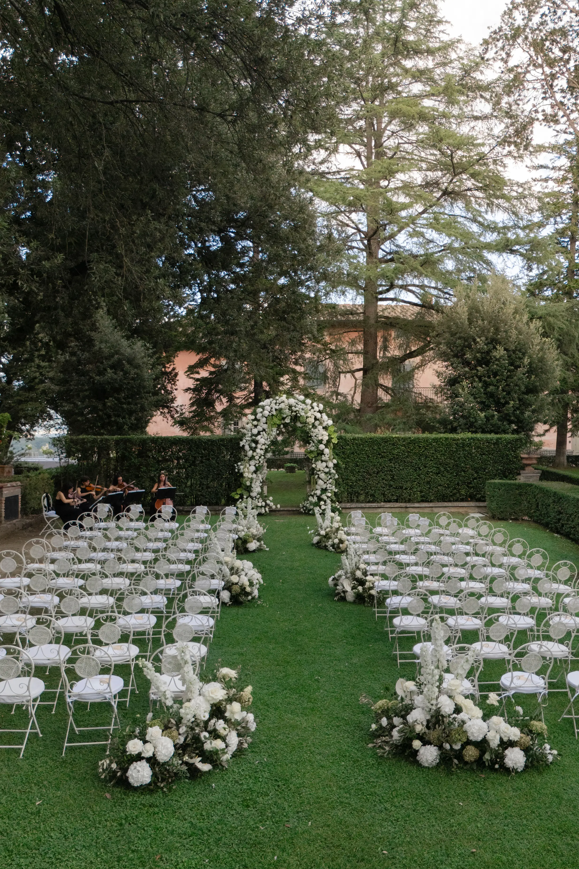Outdoor wedding ceremony setup with white chairs and floral arch