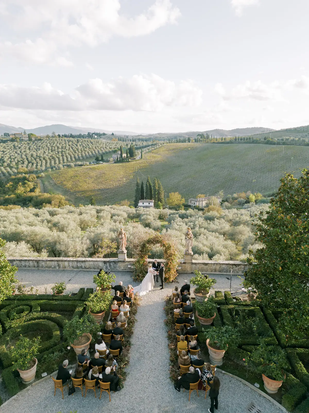 Wedding ceremony in Tuscan garden with rolling hills and olive groves backdrop