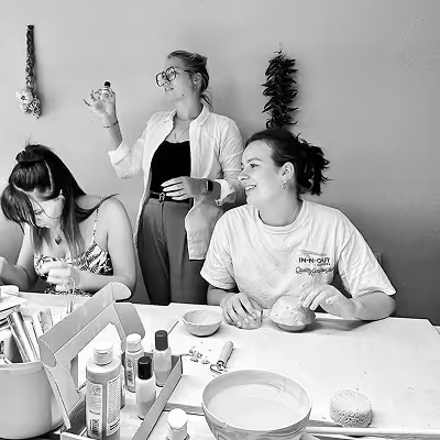 Three Artus employees engaging in a creative activity at a table with art supplies and bowls.