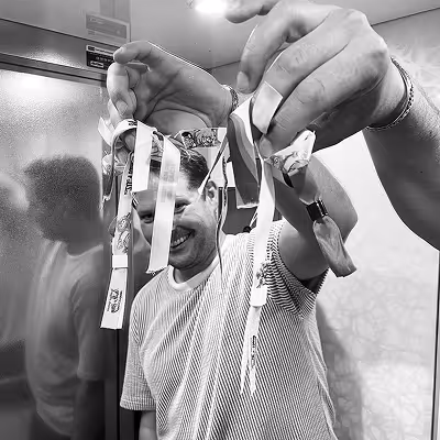 Artus employee in a striped shirt smiling and holding up several festival wristbands with his hands in an elevator.