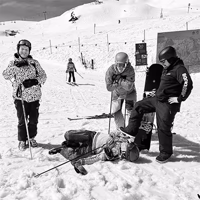 Group of four Artus employees in ski gear on a snowy slope, with one person lying on the snow and others standing around.
