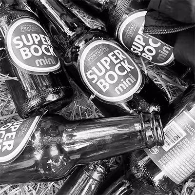 Several Super Bock Mini beer bottles lying on straw.