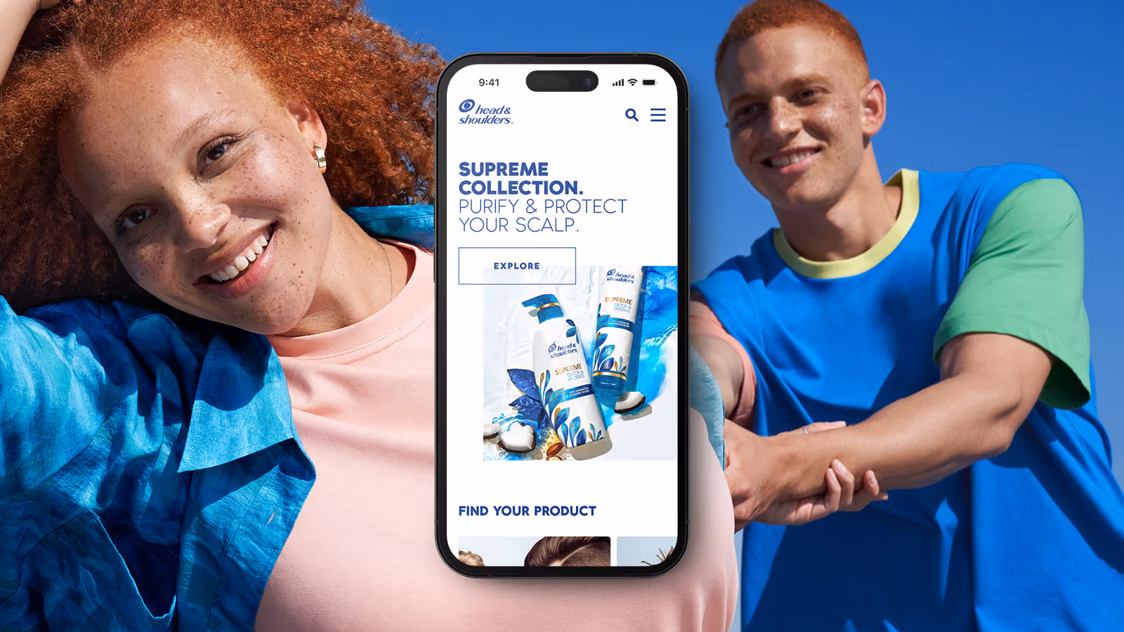 Smiling red-haired woman and man hold phone showing Head & Shoulders website.
