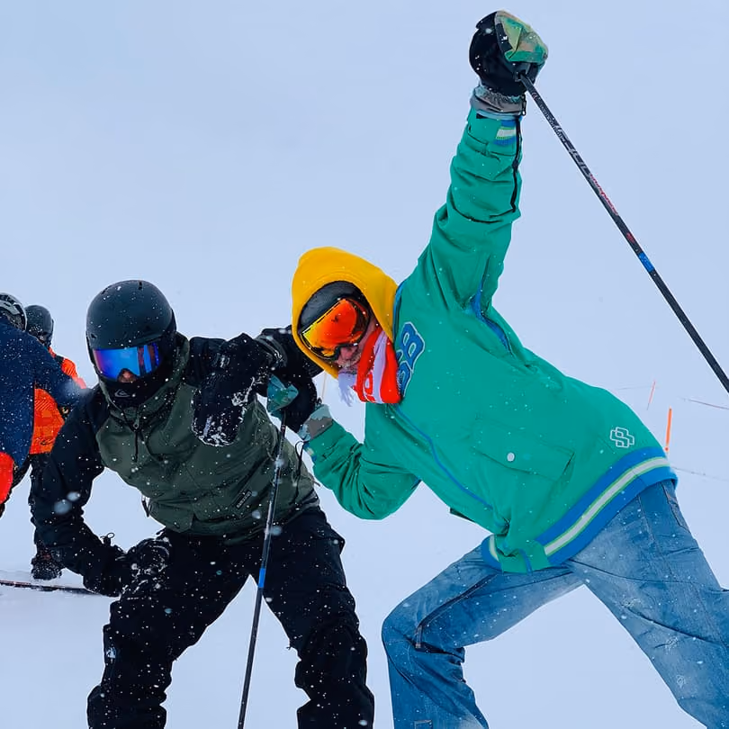 Two skiers in colorful gear posing and holding ski poles in snowy winter mountain setting.