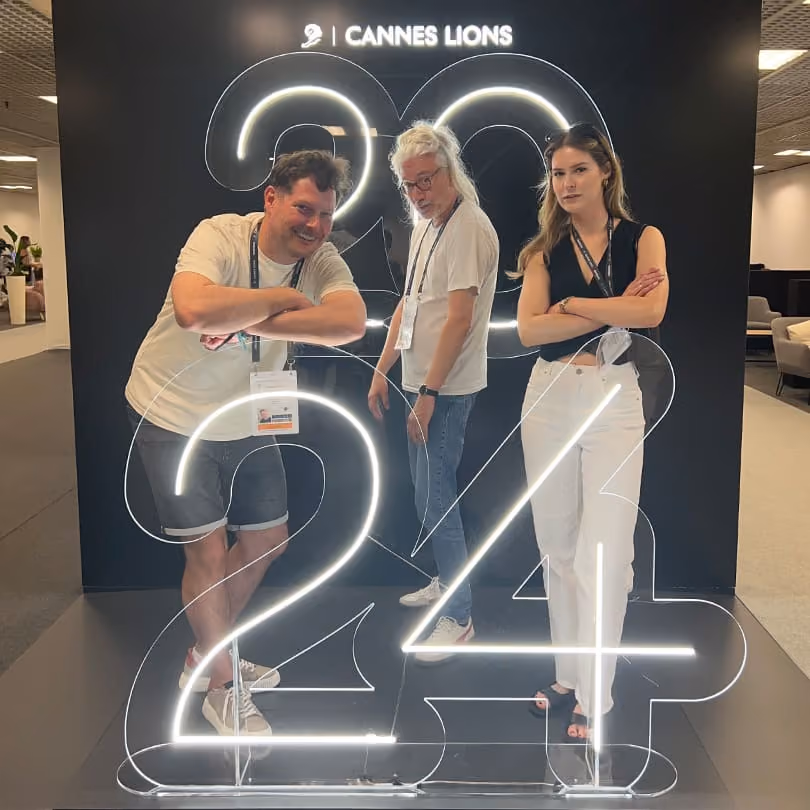 Three people posing by illuminated numbers 2024 with Cannes Lions sign above.