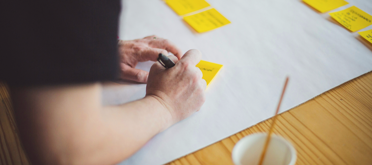 Researcher writing on sticky notes during a qualitative market research workshop