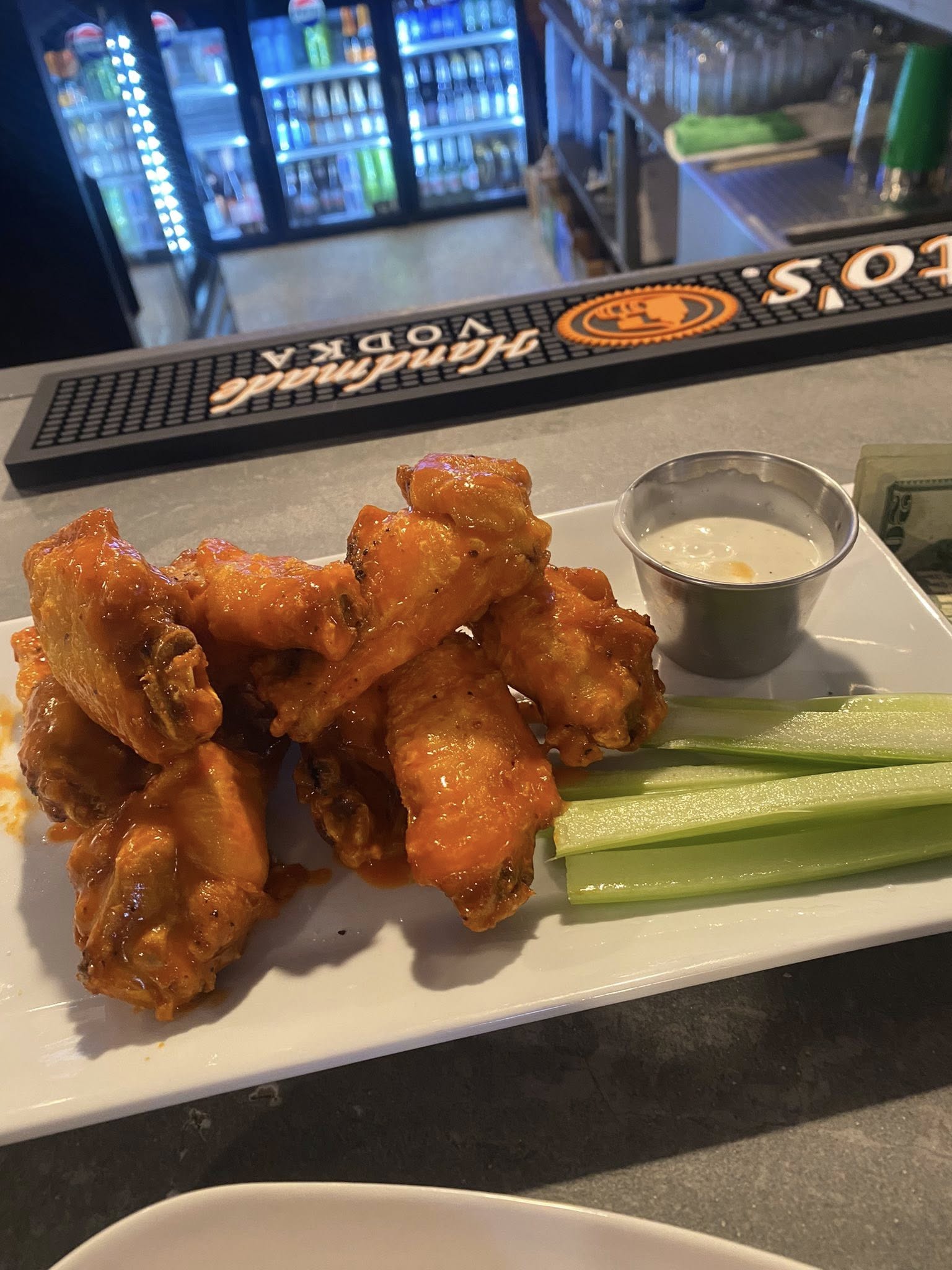 A plate of wings with a pickle on the side.