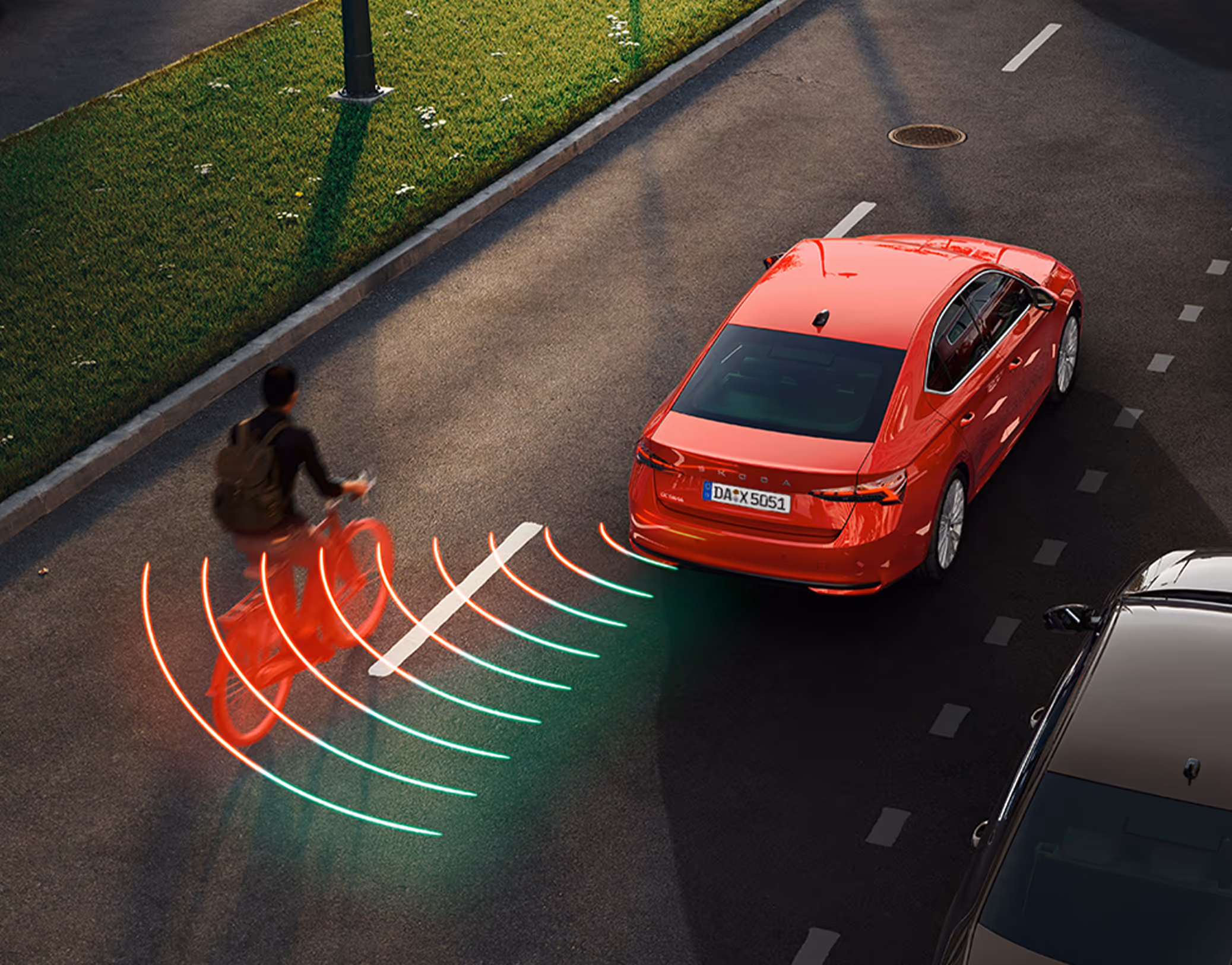 Animation des Spurwechselassistenten: Aus dem toten Winkel nähert sich von der linken Seite ein Fahrradfahrer der roten Škoda Octavia Limousine. Das System warnt vor der möglichen Gefahrensituation.