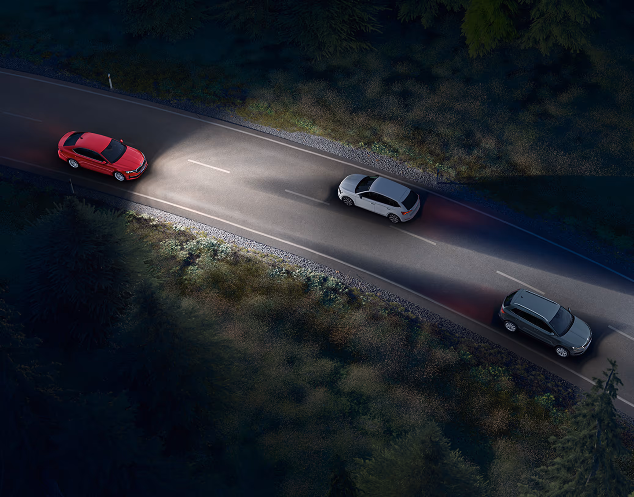 Animation des Dynamischen Fernlichtassistenten: Eine rote Škoda Octavia Limousine fährt nachts auf einer Landstraße und leuchtet die Fahrbahn mit Fernlicht aus. Das System erkennt entgegenkommende und vorausfahrende Fahrzeuge und blendet diese gezielt aus dem Lichtkegel aus, um eine Blendung zu vermeiden.