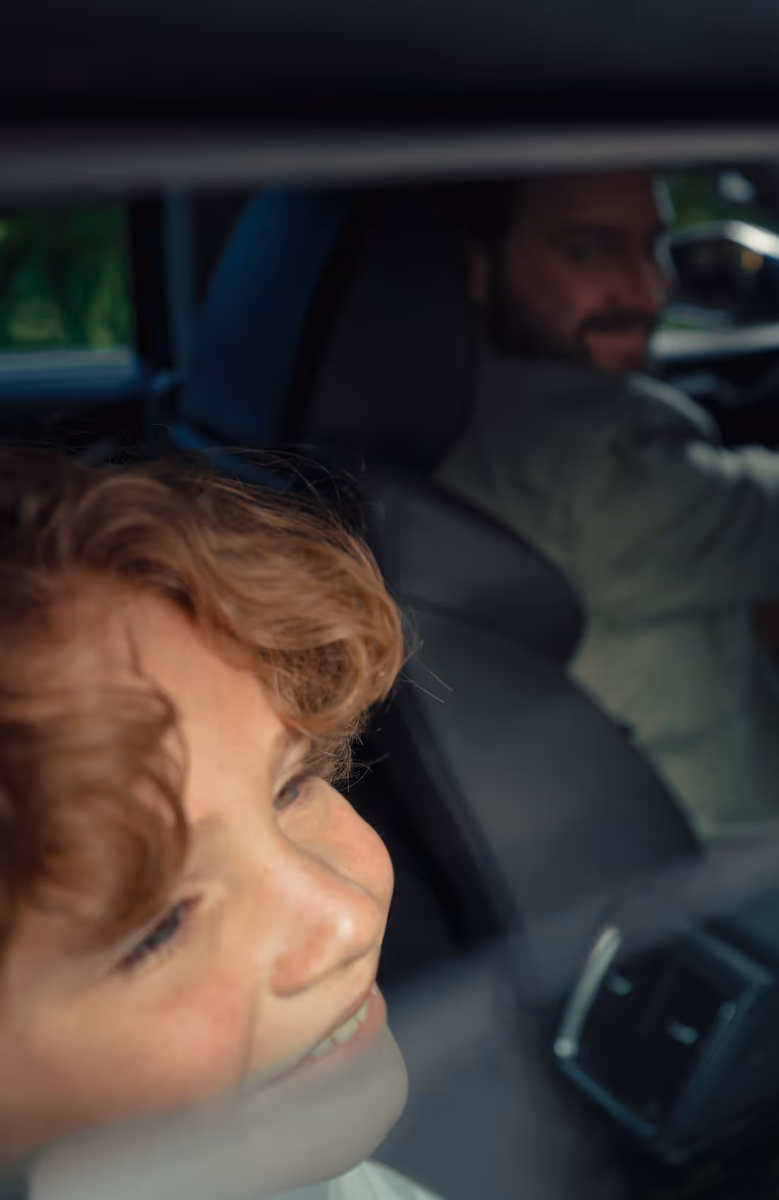 Eine Nahaufnahme der Frontpartie des Škoda Enyaq in der Farbe Olibo-Grün Metallic. Im Fokus steht der beleuchtete, markante Kühlergrill, der zusammen mit den Voll-LED-Matrix-Scheinwerfern das moderne und selbstbewusste Design unterstreicht. Unten rechts steht auf einer dunkelgrün abgesetzten Fläche der Schriftzug „Sicherheit und Assistenten“.