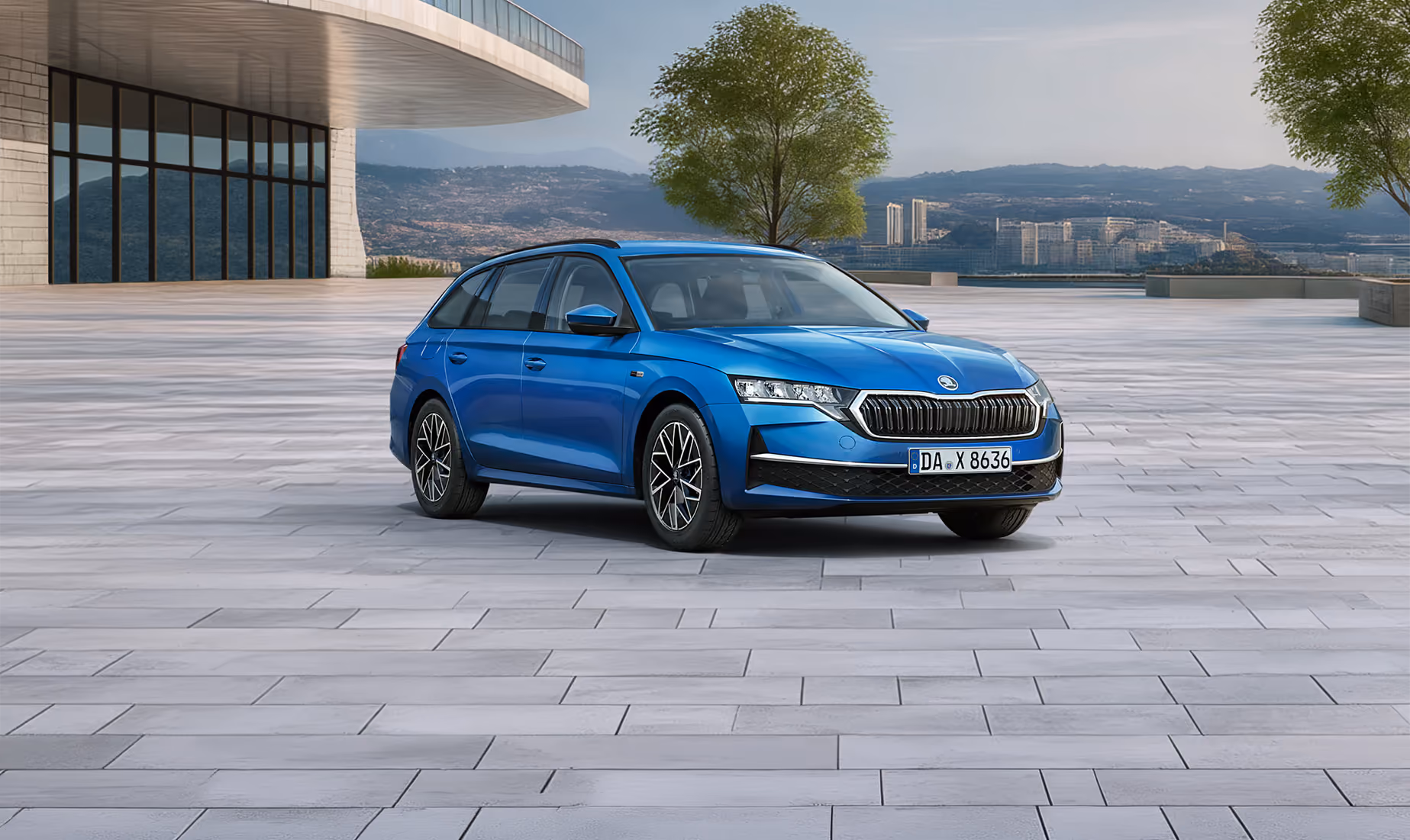 Das Bild zeigt das Balance-Sondermodell Škoda Octavia Combi in der Farbe Race-Blau Metallic aus der vorderen linken schrägen Perspektive auf einem weitläufigen, gepflasterten Platz vor einer Stadtkulisse. Zu sehen sind Exterieur-Details wie die silbernen Leichtmetallfelgen, der Kühlergrill mit Chromrahmen sowie die schwarze Dachreling. Am unteren linken Bildrand hebt ein hellgrüner Störer einen Preisvorteil sowie die inkludierte 5-Jahres-Garantie hervor.