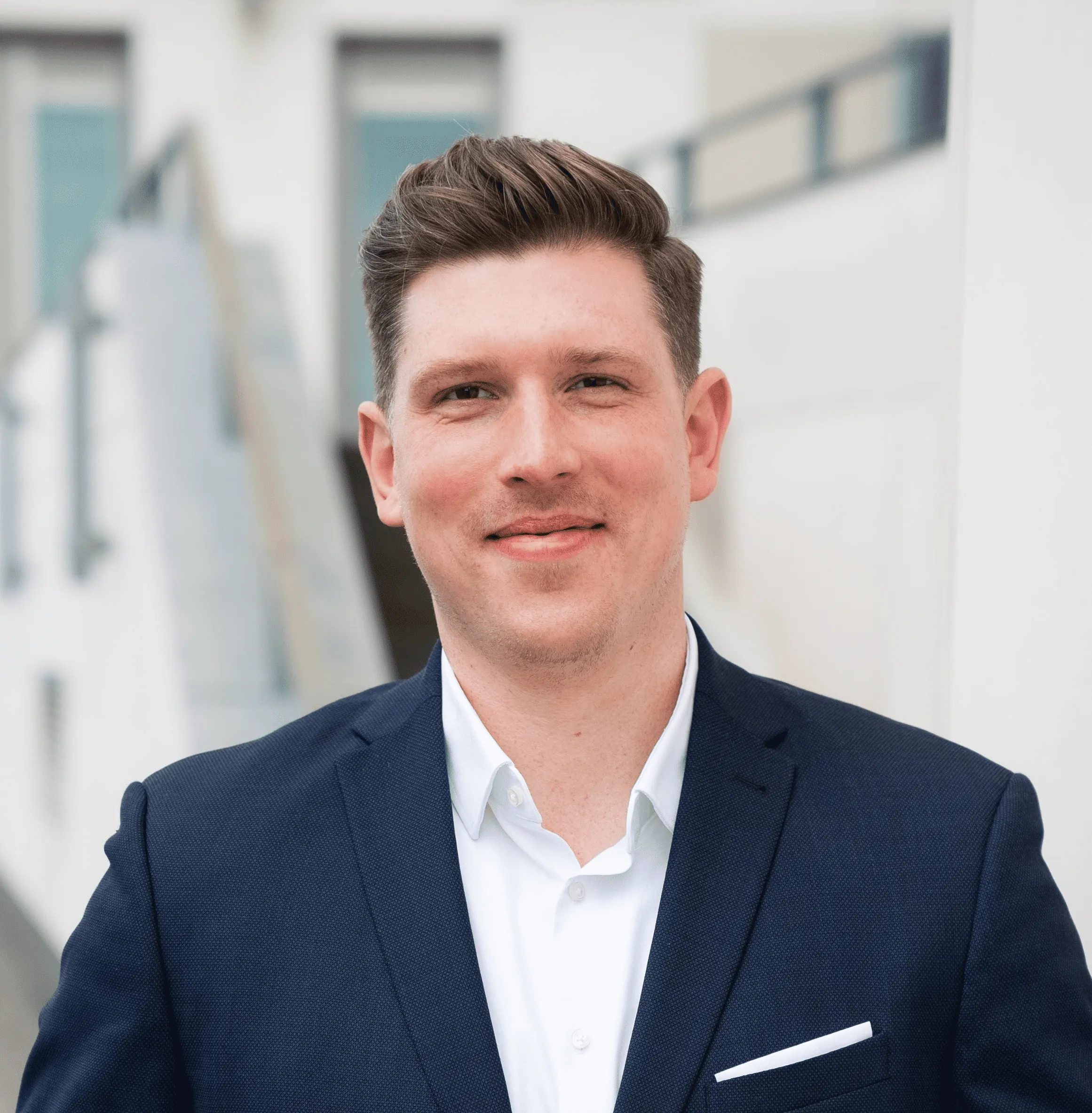 Porträt von Sebastian Michalski vor einem unscharfen Hintergrund mit weißen Bürogebäuden.