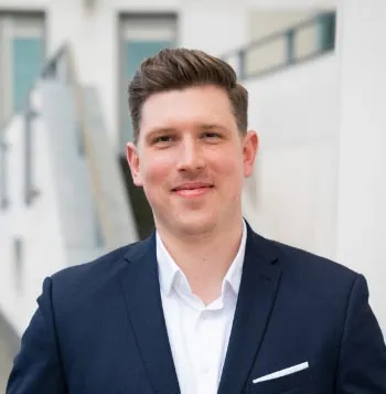 Porträt von Sebastian Michalski vor einem unscharfen Hintergrund mit weißen Bürogebäuden.