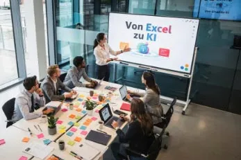 Person präsentiert einem Team bei einem Workshop mit dem Thema 'Von Excel zu KI' an einem Bildschirm.
