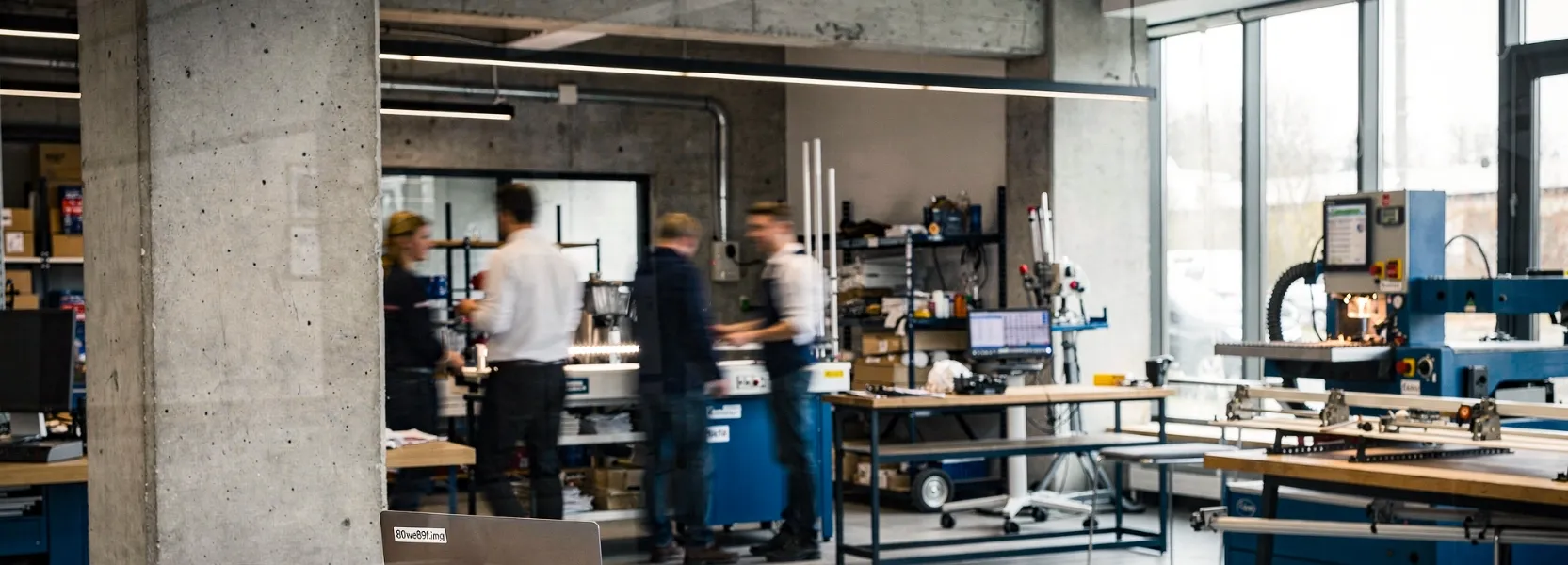 Vier Personen arbeiten in einem modernen, industriellen Labor mit Maschinen und Ausrüstung.