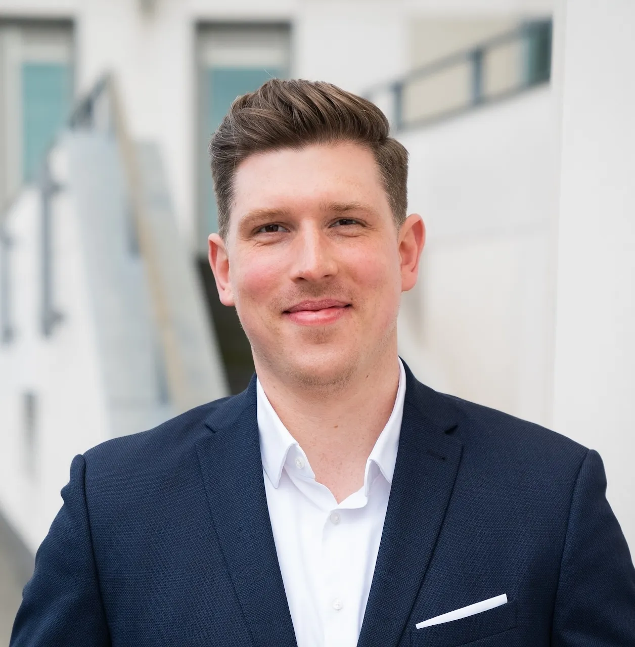 Porträt von Sebastian Michalski vor einem unscharfen Hintergrund mit weißen Bürogebäuden.