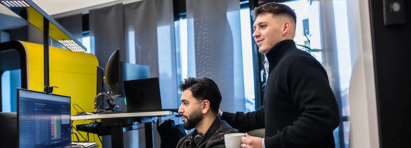 Fünf Kollegen in einem modernen Büro geben sich lachend High-Fives und wirken motiviert.