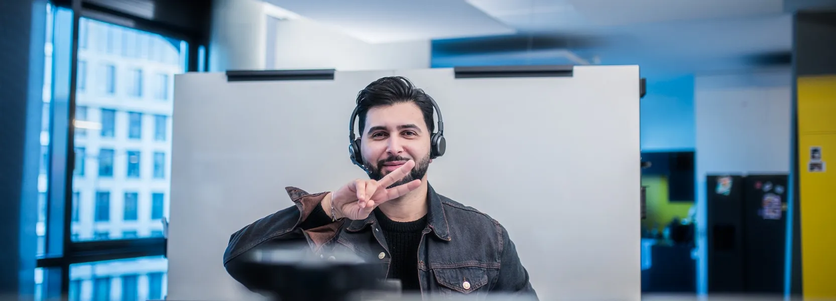 Ein Mann gibt einen Vortrag vor einem Bildschirm mit der Überschrift 'Was sind virtuelle Agenten?' und vier Informationsfeldern zu Sprachverarbeitung, automatisierten Aufgaben, maschinellem Lernen und Plattformintegration.