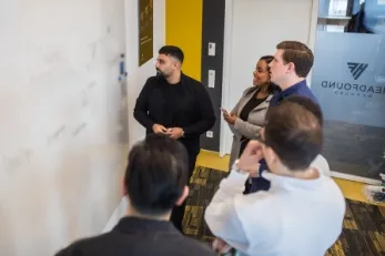 Männer und Frauen in einem modernen Konferenzraum, die eine Präsentation über KI vor einem großen Bildschirm anhören.