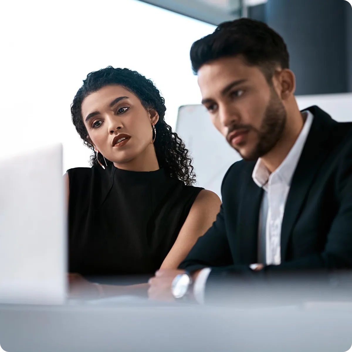 un hombre y una mujer en traje viendo una computadora