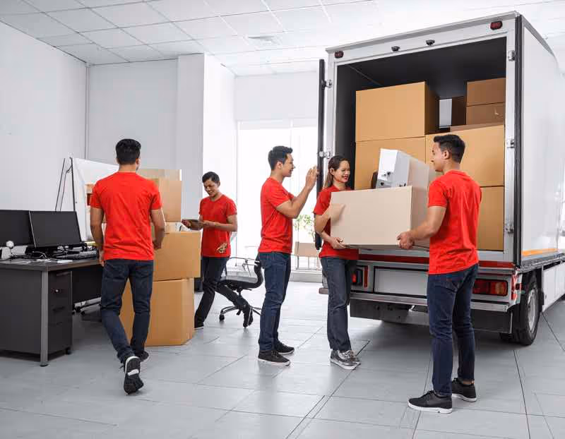 Professional moving crew in red shirts loading office boxes onto a truck. Keywords: office moving Austin TX, commercial movers, corporate relocation services.