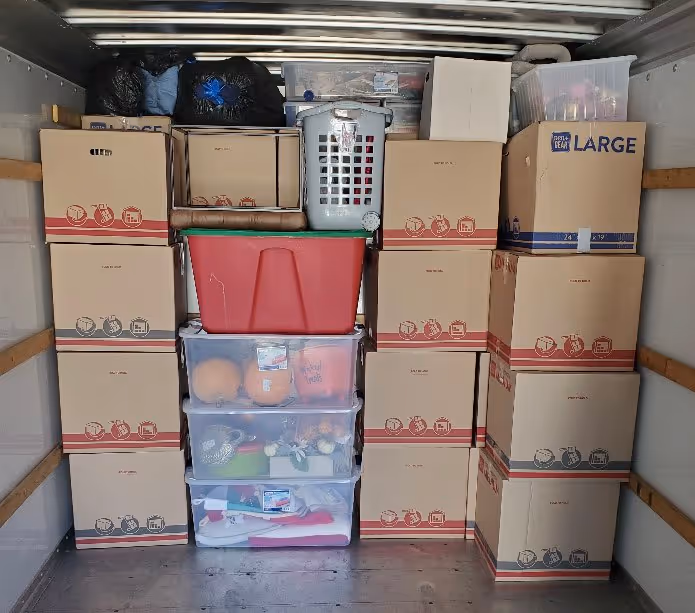 Boxes and clear plastic bins packed tightly in a moving truck, showing efficient loading of household goods for a move to Austin, TX.