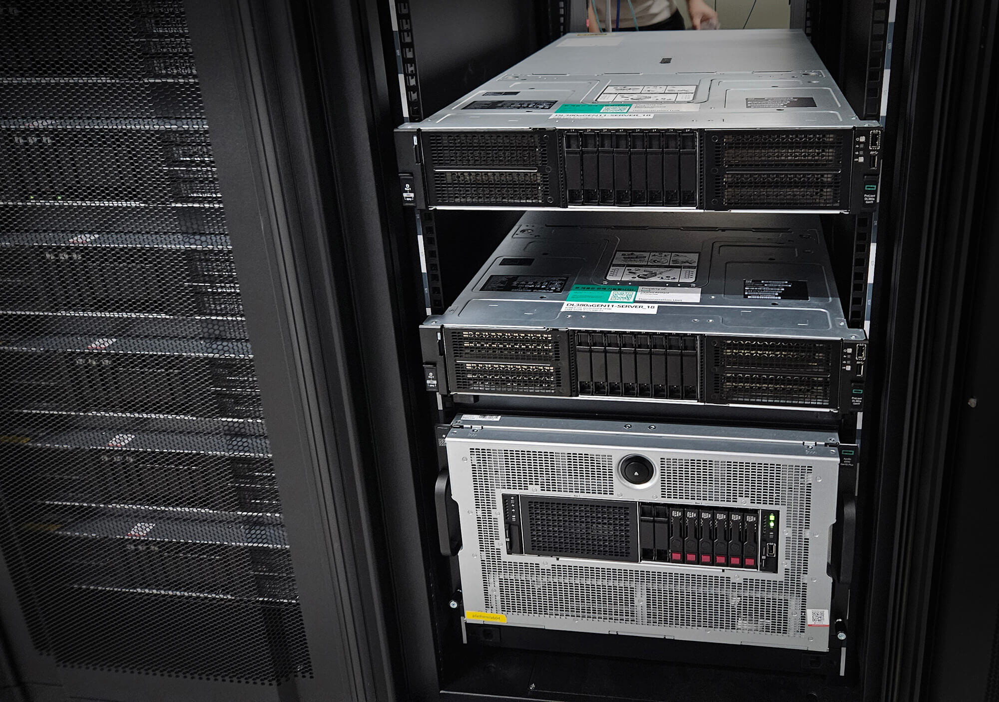 Close-up view of multiple servers installed in a data center rack, with visible ventilation grilles, drive bays, and status indicators.