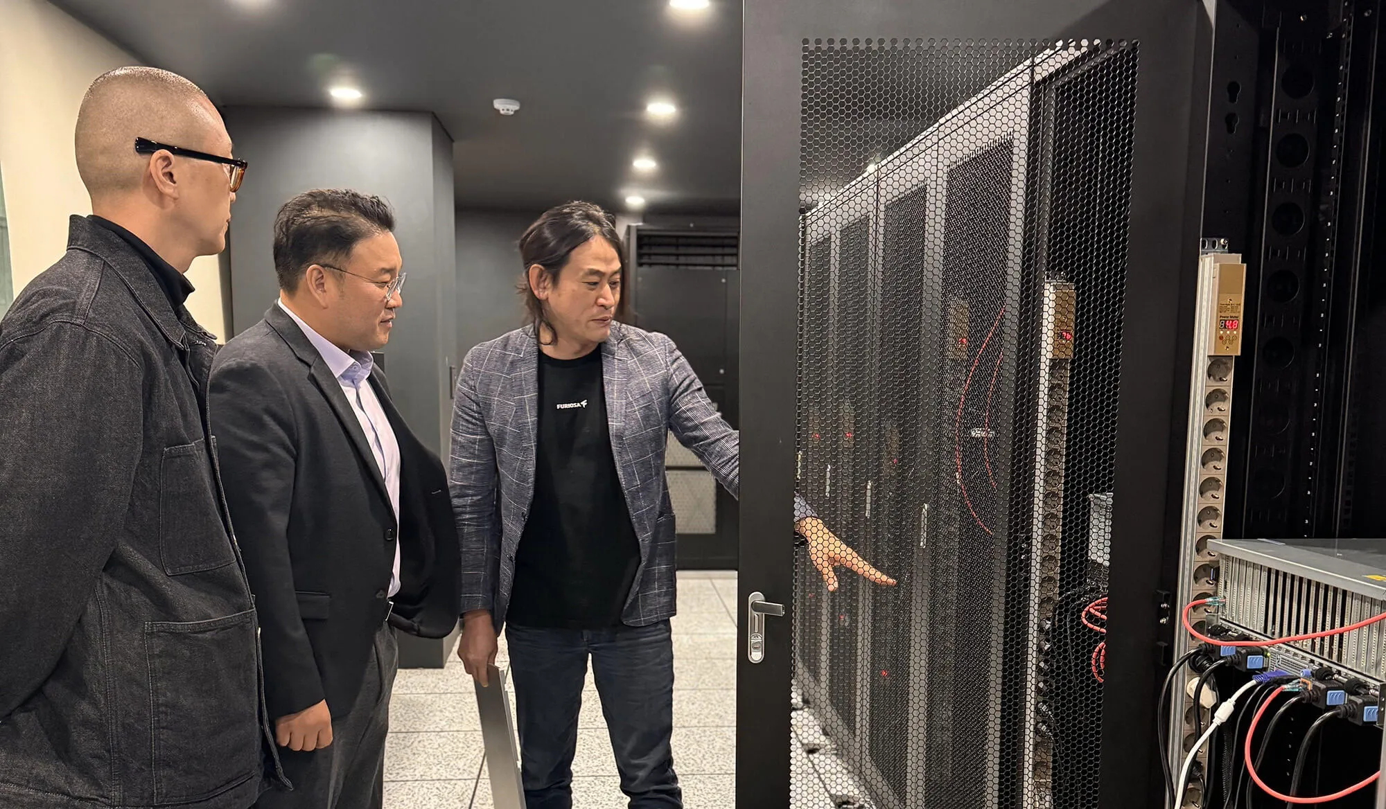 Three professionals touring a data center, examining server racks and discussing AI infrastructure.