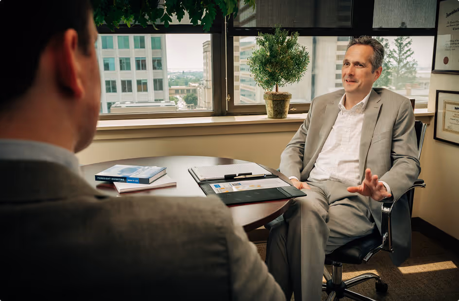 James H. Lee and a man having a discussion in an office with cityscape visible through the window.