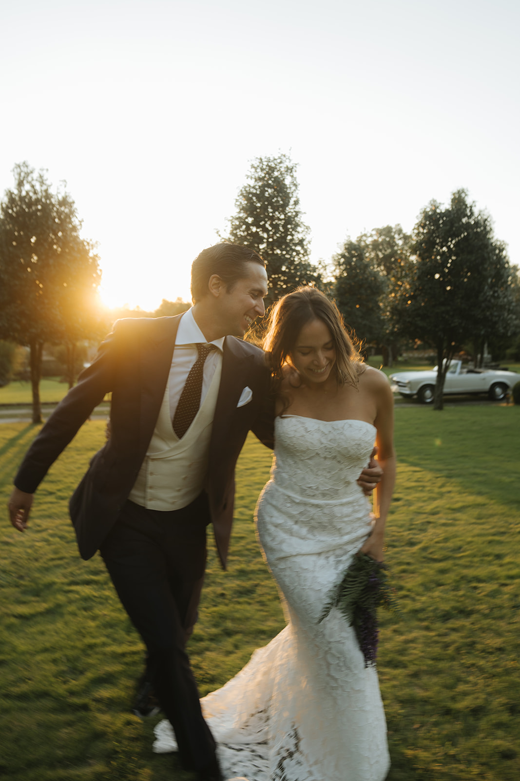 Elegant outdoor wedding setup with round tables, gold chairs, white floral arrangements, and hanging crystal chandeliers.