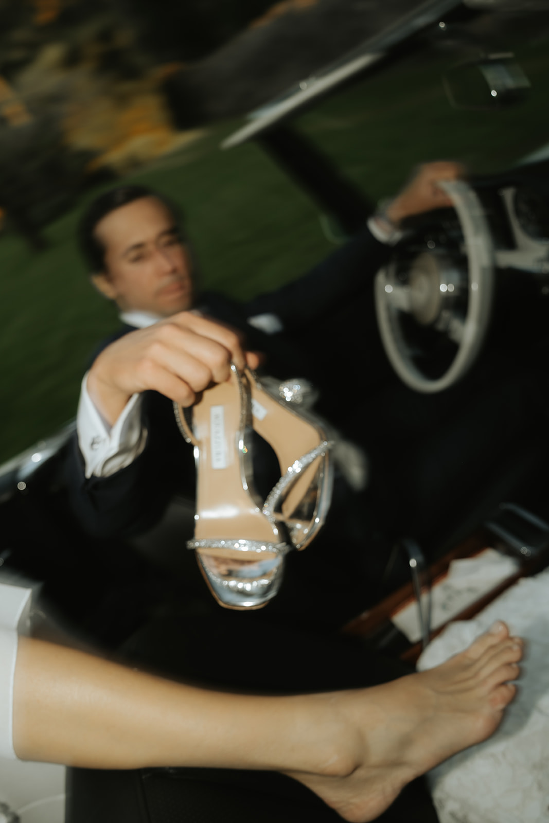 Close-up of a person fastening a gold cufflink on another person’s white dress shirt cuff.