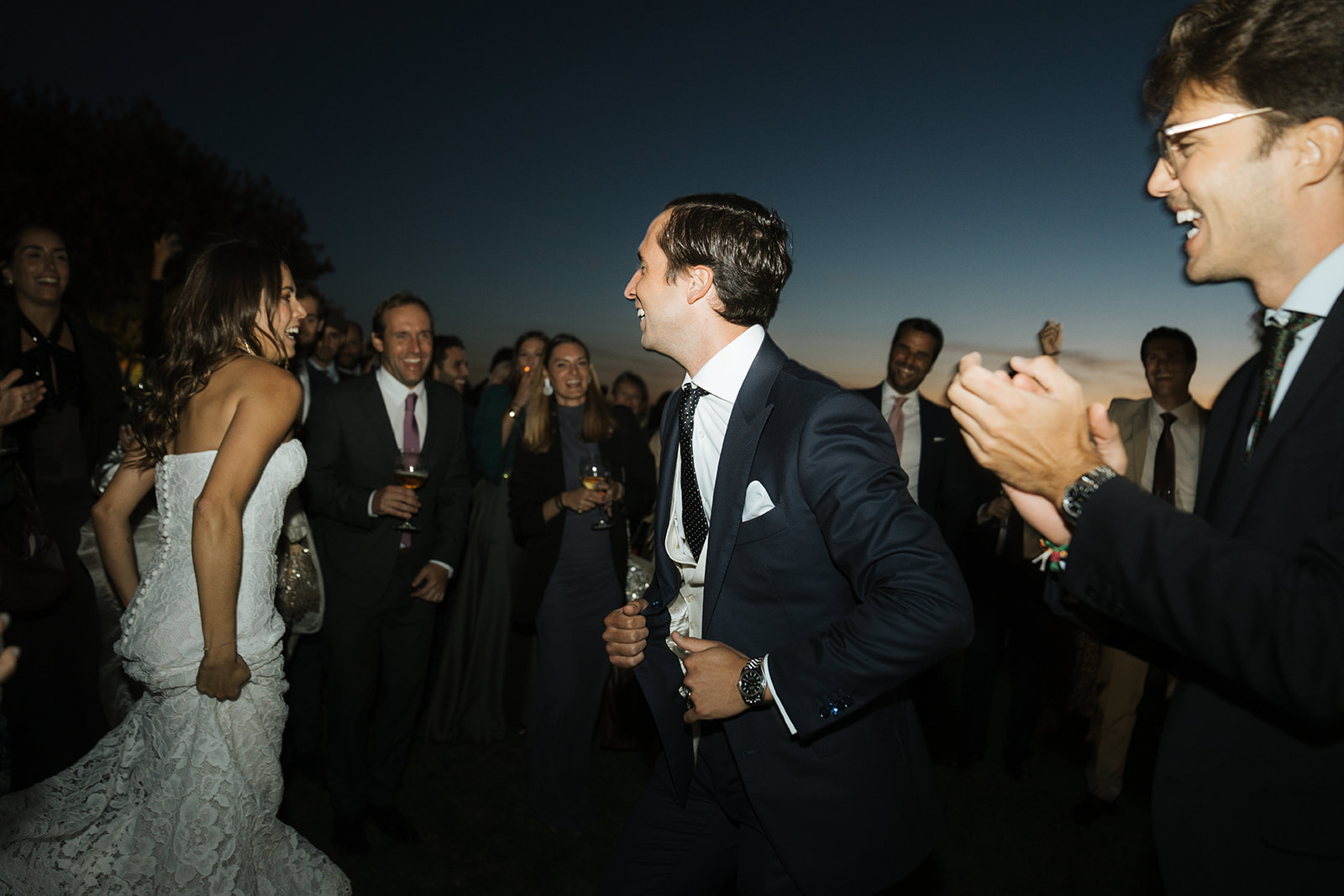 Black and white photo of a man adjusting his formal shirt and bow tie while looking at his reflection in an oval mirror.