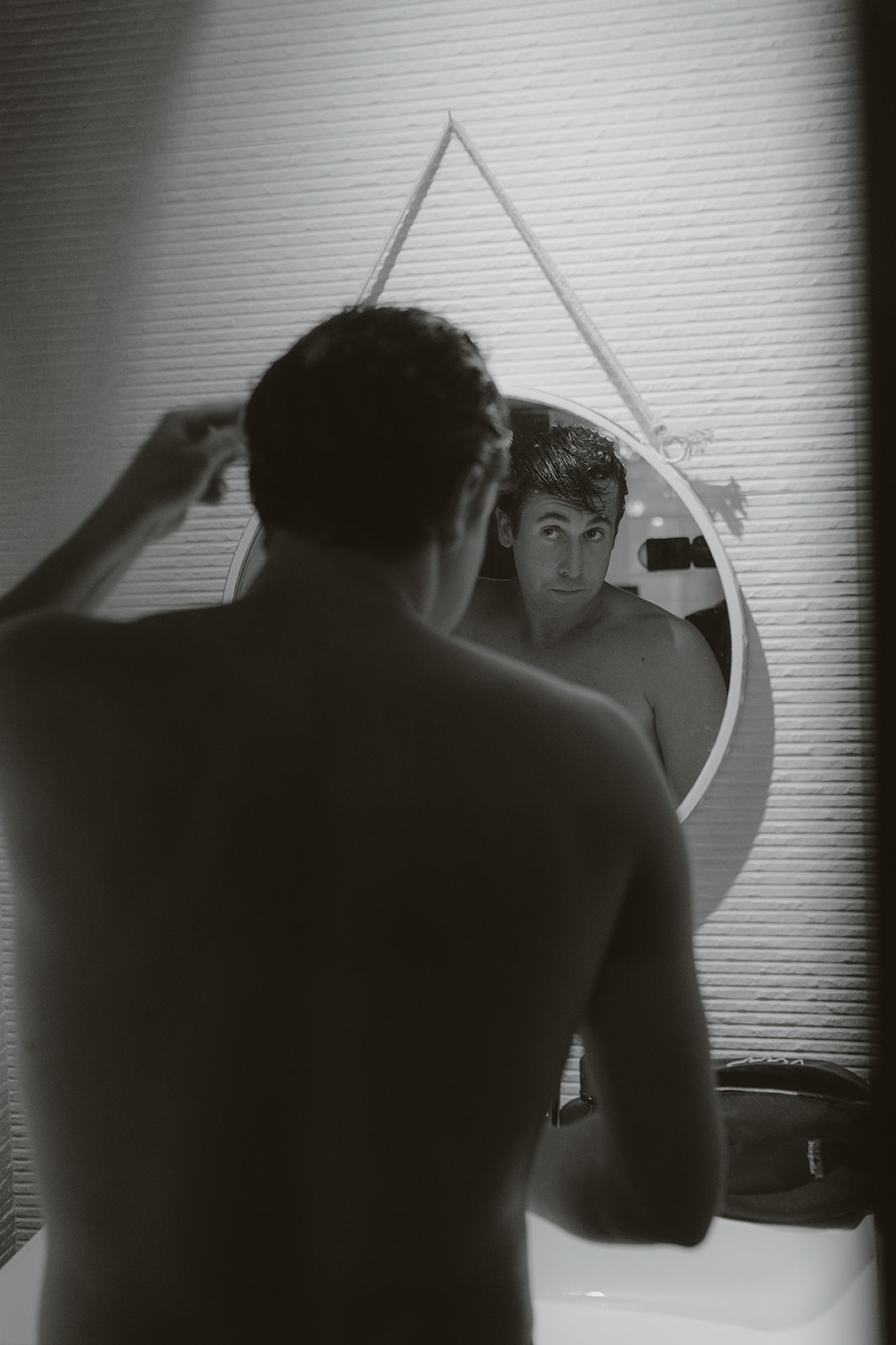 Elegant white off-shoulder wedding dress hanging on ornate cream and gold wardrobe with matching heels and veil on nearby chair.
