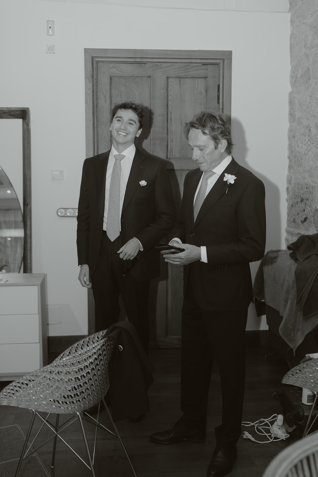 Pair of black patent leather and suede oxford dress shoes on a light marble floor.