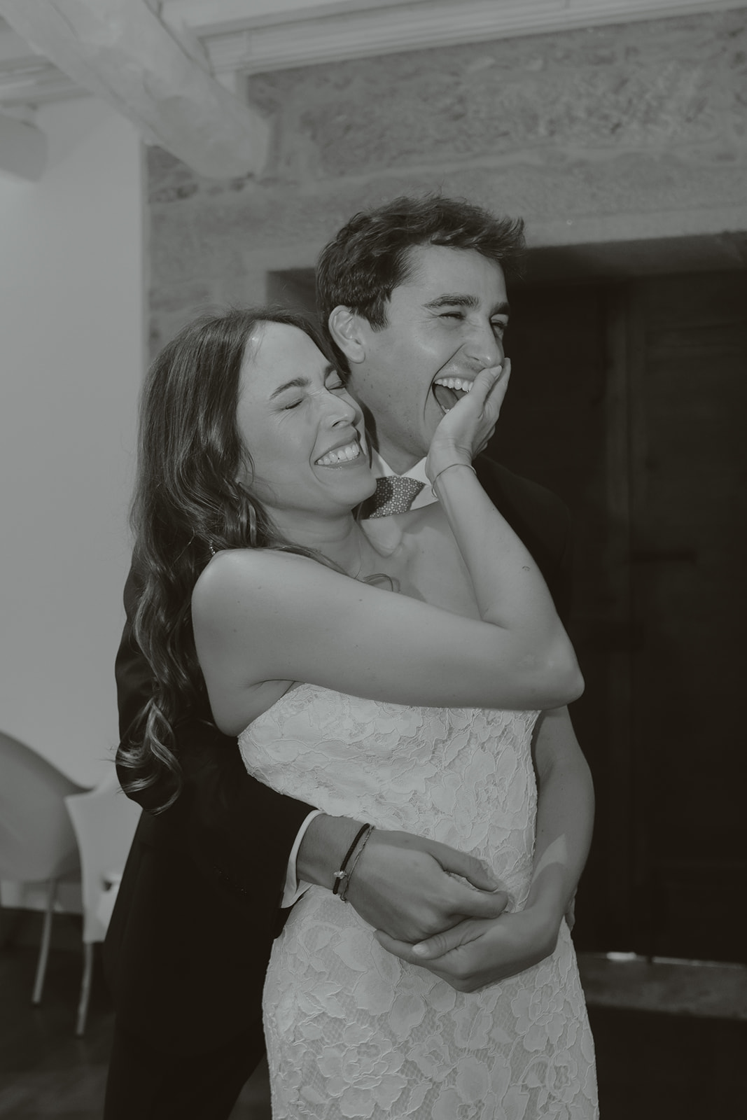 Woman in silky white robe sitting on a brown couch holding a bouquet of white roses.