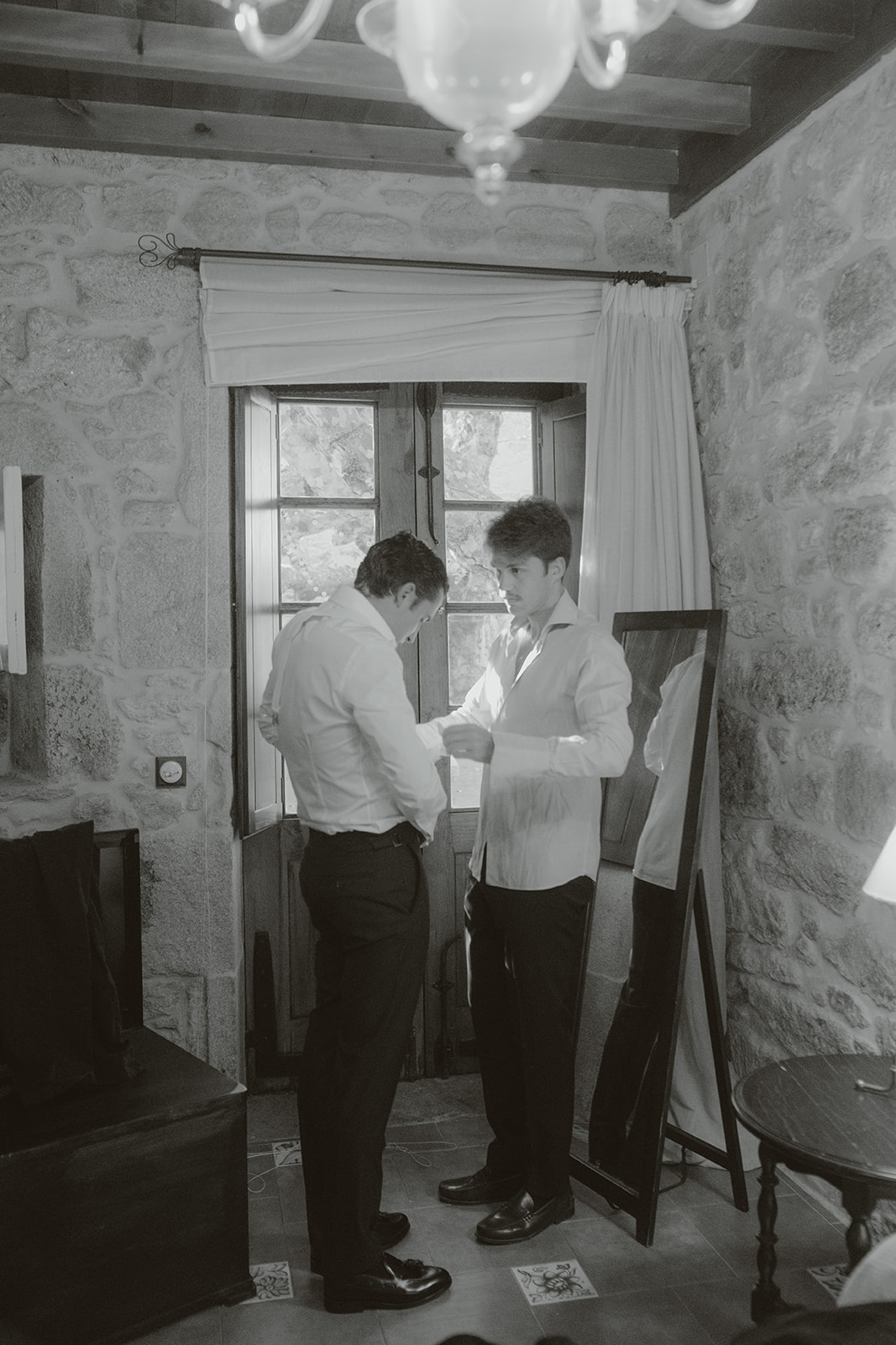 Two men in suits sharing an emotional embrace indoors.