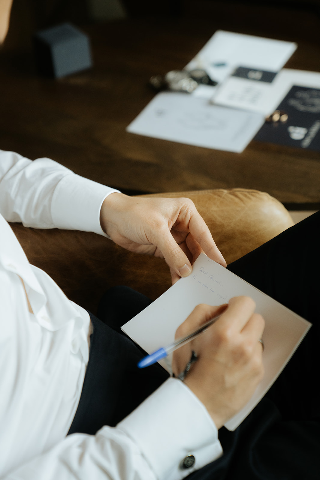 Elegant white off-shoulder wedding dress hanging on ornate cream and gold wardrobe with matching heels and veil on nearby chair.
