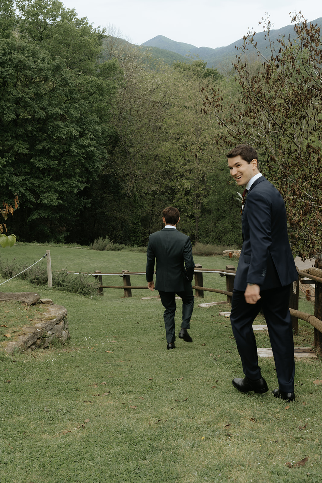 Bride and groom holding hands and smiling while walking down ornate staircase with stained glass windows and statue in the background.